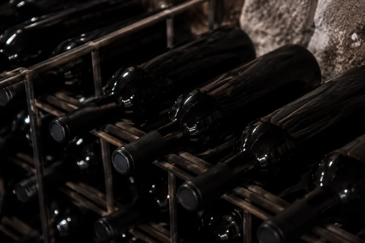 Bouteilles de vin sans étiquette alignées sur un rack métallique dans une cave